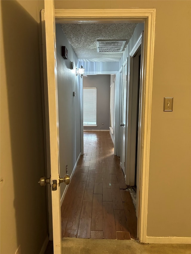 corridor featuring a textured ceiling and dark hardwood / wood-style floors