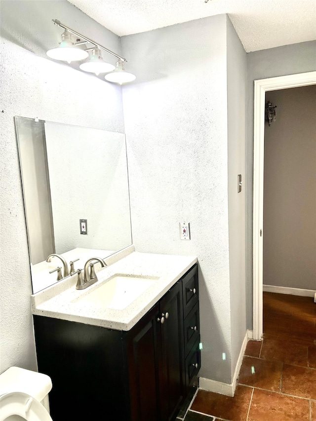 bathroom featuring toilet, a textured ceiling, vanity with extensive cabinet space, and tile flooring