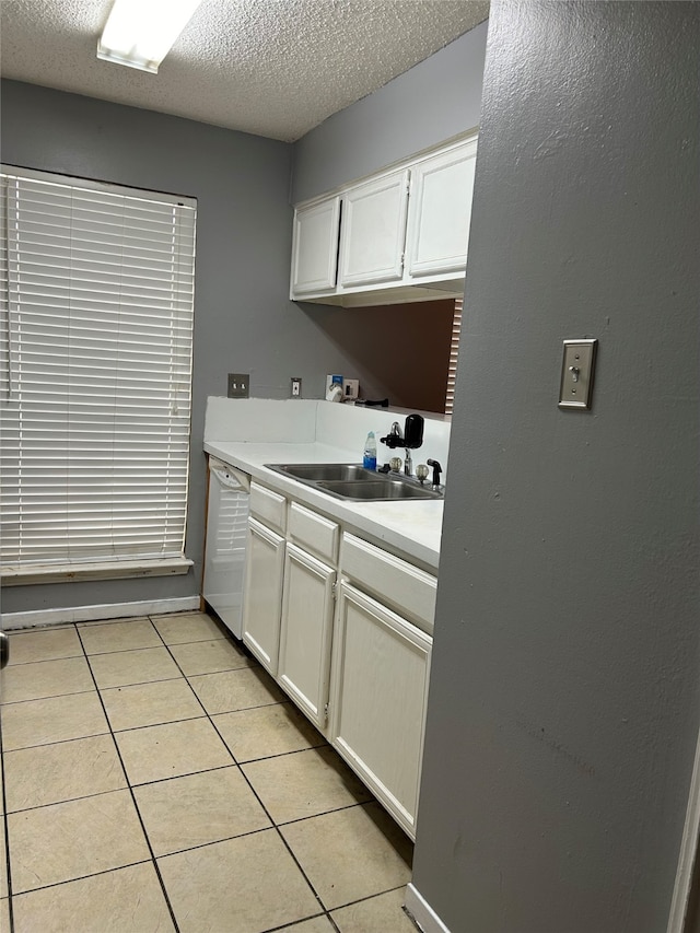 kitchen featuring light tile flooring, a textured ceiling, dishwasher, sink, and white cabinetry