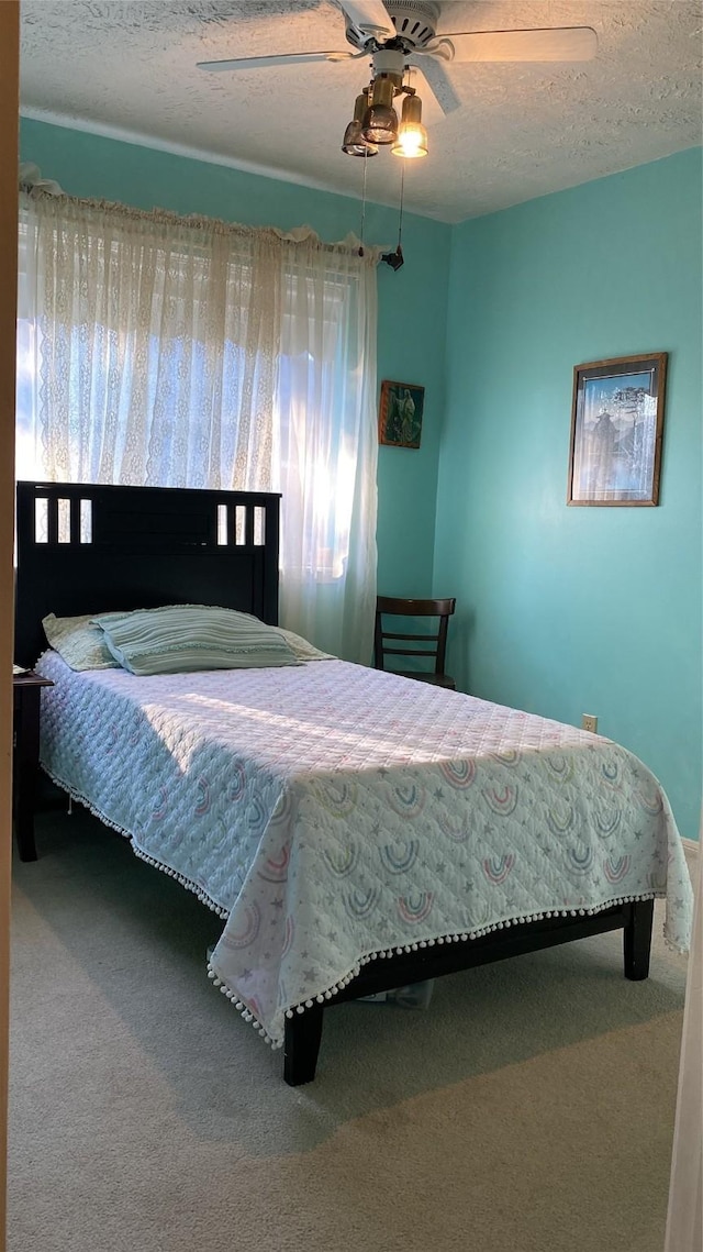 bedroom with ceiling fan, carpet, and a textured ceiling