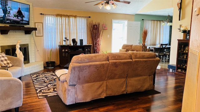 living room with a brick fireplace, dark hardwood / wood-style floors, and ceiling fan