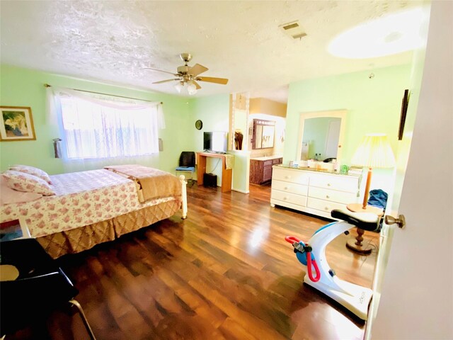 bedroom featuring ceiling fan, connected bathroom, a textured ceiling, and dark hardwood / wood-style flooring