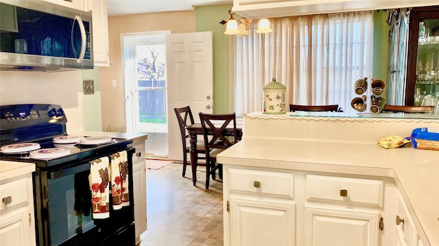 kitchen featuring pendant lighting, black electric range oven, white cabinetry, and a healthy amount of sunlight