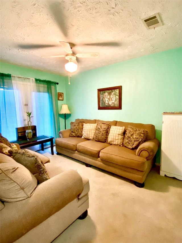 carpeted living room featuring a textured ceiling and ceiling fan