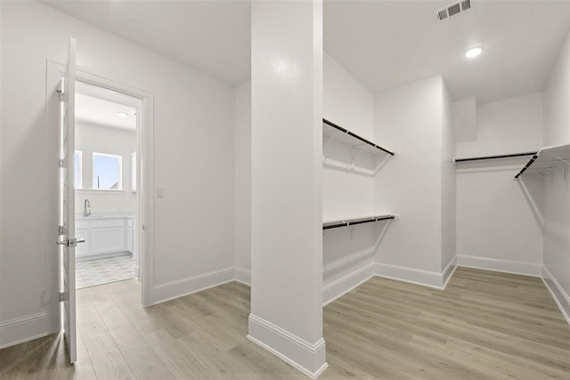 spacious closet with light hardwood / wood-style floors and sink