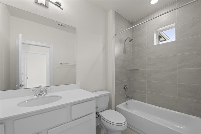 full bathroom featuring tiled shower / bath, vanity, and toilet