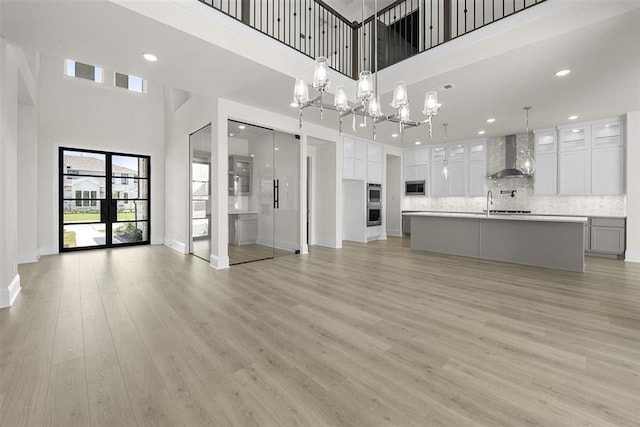 unfurnished living room featuring a high ceiling, light hardwood / wood-style floors, and french doors