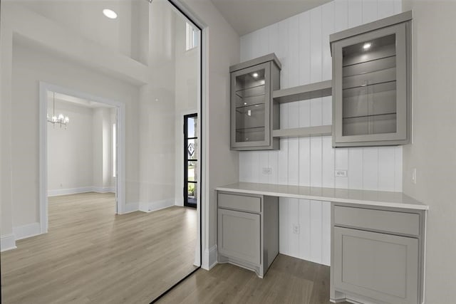 kitchen featuring light hardwood / wood-style flooring, wooden walls, a notable chandelier, and gray cabinetry