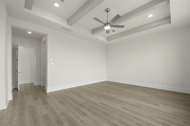 spare room with a tray ceiling, light hardwood / wood-style floors, and ceiling fan