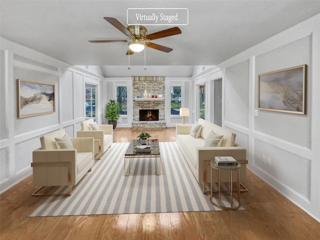 living room with hardwood / wood-style flooring, a fireplace, brick wall, and ceiling fan