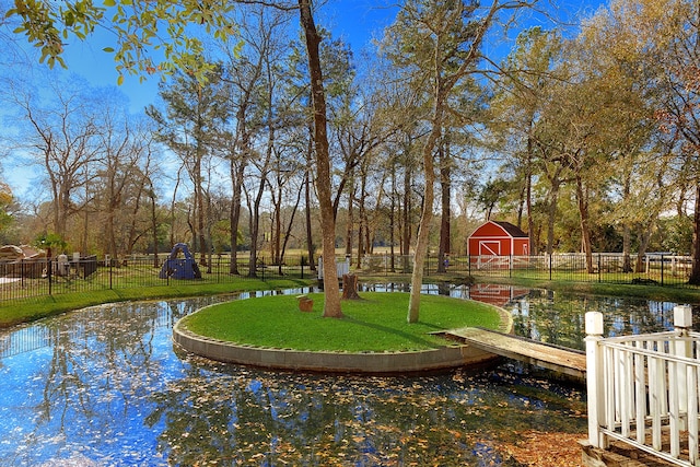 view of property's community featuring a water view, a yard, and an outdoor structure