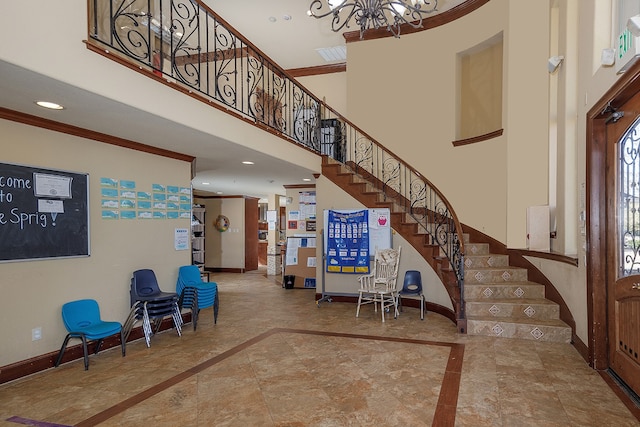 entryway featuring ornamental molding, a towering ceiling, and a chandelier