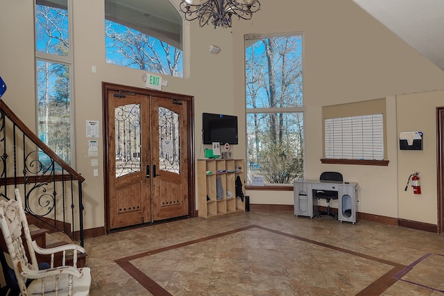 foyer with french doors, a towering ceiling, and a chandelier