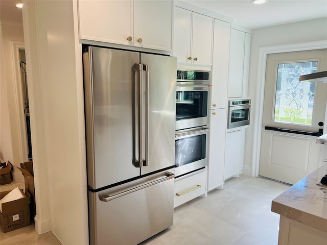 kitchen featuring appliances with stainless steel finishes, light stone counters, and white cabinetry