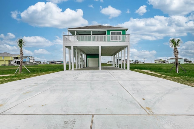 coastal home with a front lawn, a balcony, a garage, and a carport