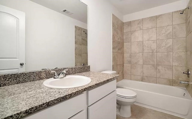 full bathroom with tile floors, toilet, large vanity, and tiled shower / bath