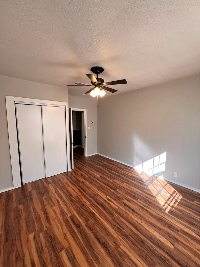 unfurnished bedroom with dark hardwood / wood-style floors, a textured ceiling, a closet, and ceiling fan