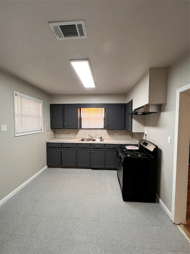 kitchen featuring wall chimney range hood, light tile floors, sink, gray cabinets, and black stove