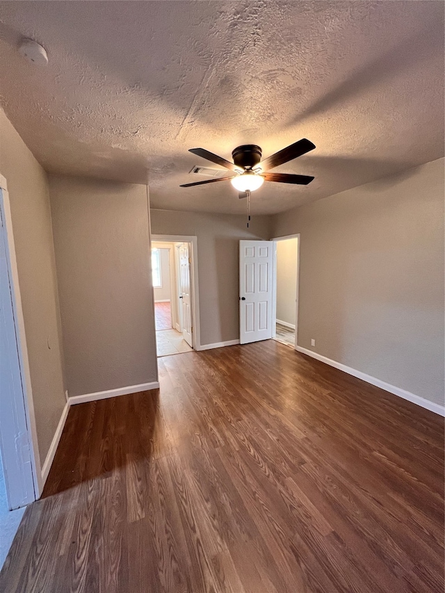 empty room with dark hardwood / wood-style flooring, ceiling fan, and a textured ceiling