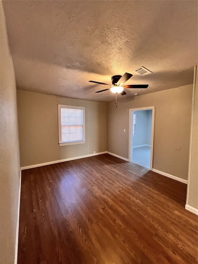 empty room featuring a textured ceiling, ceiling fan, and dark wood-type flooring