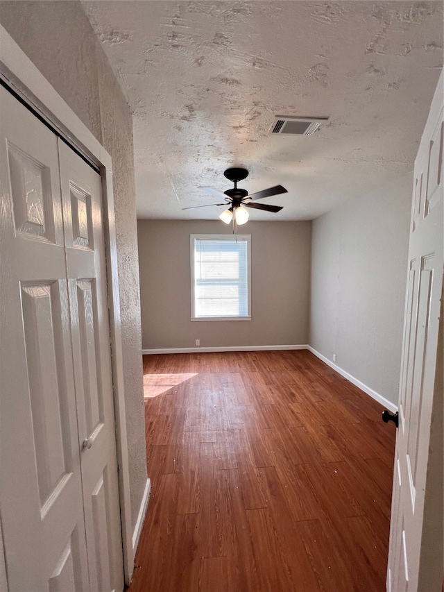 unfurnished room featuring dark hardwood / wood-style flooring, ceiling fan, and a textured ceiling