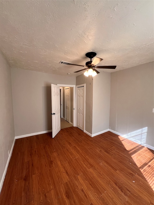 unfurnished bedroom with ceiling fan, dark wood-type flooring, and a textured ceiling