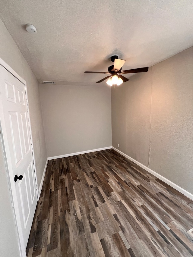 spare room featuring ceiling fan, dark wood-type flooring, and a textured ceiling