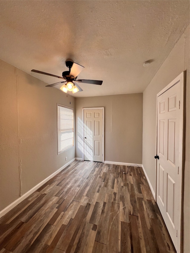 unfurnished bedroom featuring ceiling fan, dark wood-type flooring, and a textured ceiling