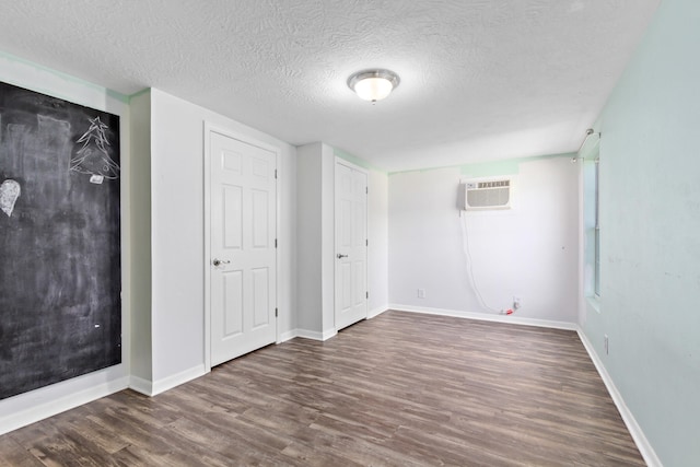 interior space with a wall mounted air conditioner, dark hardwood / wood-style flooring, and a textured ceiling