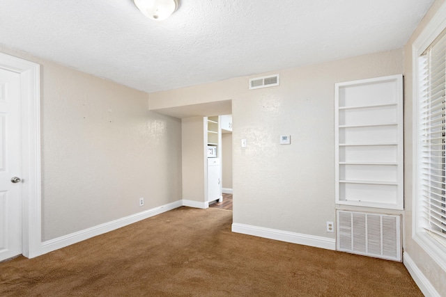 carpeted empty room with built in features and a textured ceiling