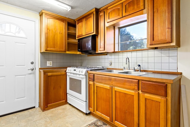 kitchen featuring backsplash, white range with gas stovetop, sink, and light tile flooring