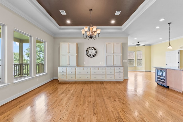 unfurnished living room with a tray ceiling, light hardwood / wood-style floors, and ceiling fan with notable chandelier