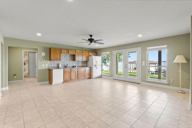 unfurnished living room with light tile flooring, ceiling fan, and sink