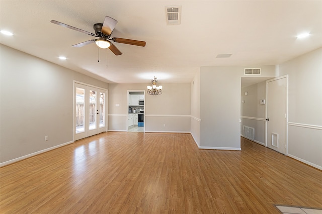 unfurnished living room with ceiling fan with notable chandelier, light hardwood / wood-style flooring, and french doors