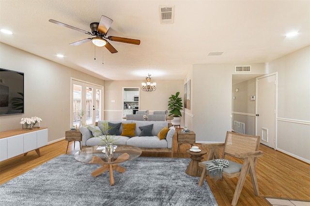 living room with hardwood / wood-style flooring, ceiling fan with notable chandelier, and french doors