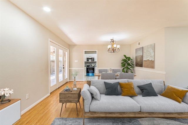 living room with light hardwood / wood-style floors, french doors, and a chandelier