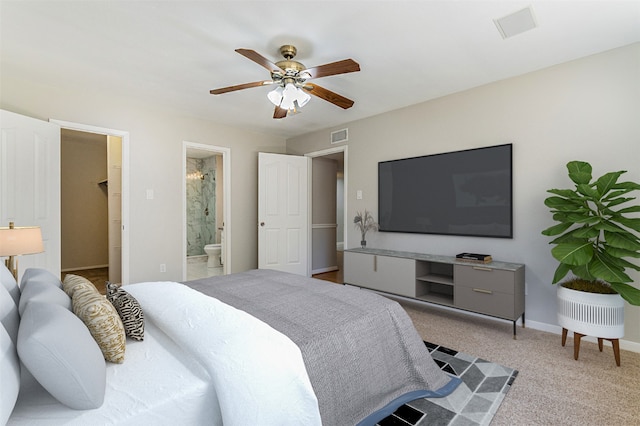 carpeted bedroom featuring ensuite bathroom, a walk in closet, and ceiling fan