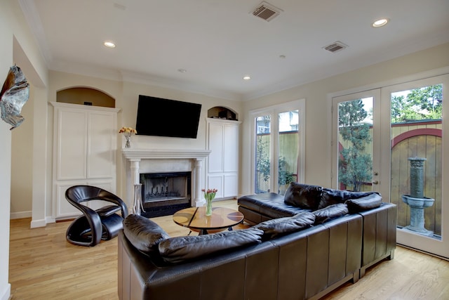 living room featuring a healthy amount of sunlight, ornamental molding, light hardwood / wood-style floors, and a high end fireplace