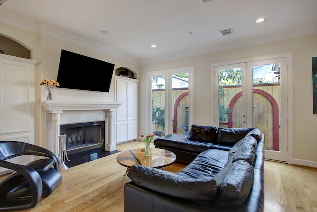 living room with french doors, crown molding, and light wood-type flooring