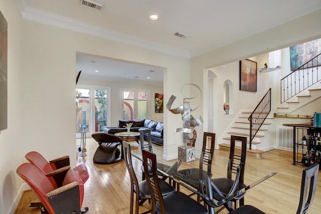 dining space featuring ornamental molding and light hardwood / wood-style flooring