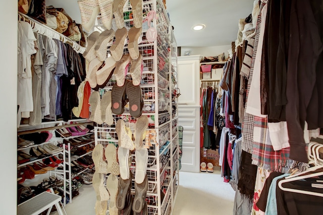 walk in closet with light carpet