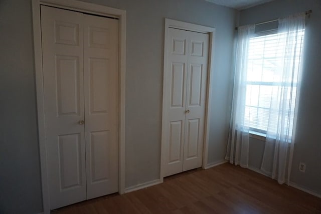 unfurnished bedroom with two closets and hardwood / wood-style flooring