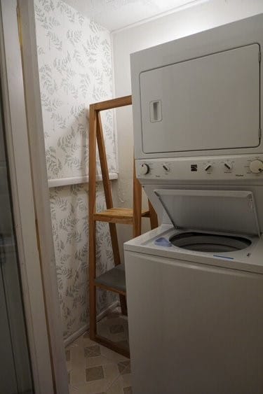 laundry room featuring light tile flooring and stacked washer and clothes dryer