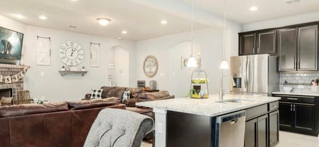 kitchen with pendant lighting, a fireplace, backsplash, stainless steel appliances, and light tile floors