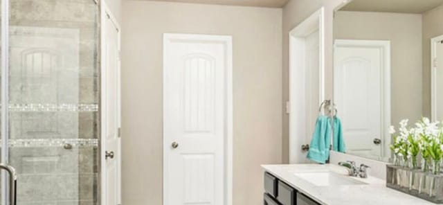 bathroom featuring vanity and a shower with door