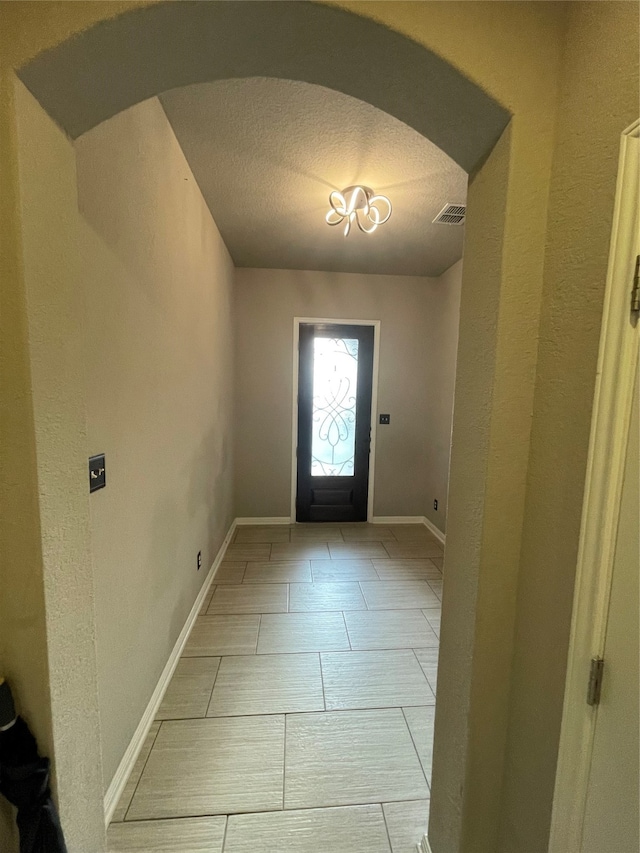 doorway to outside featuring tile floors and a textured ceiling