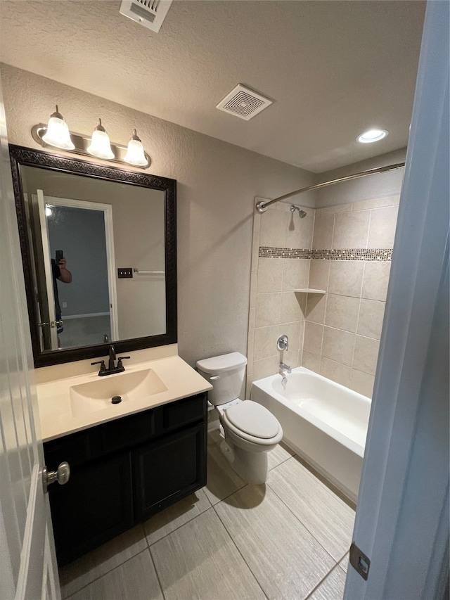 full bathroom featuring vanity with extensive cabinet space, toilet, tiled shower / bath combo, a textured ceiling, and tile floors