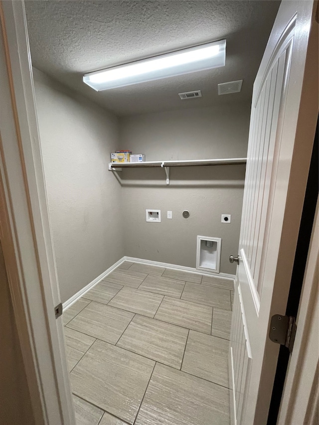 clothes washing area featuring hookup for an electric dryer, hookup for a washing machine, tile flooring, a textured ceiling, and hookup for a gas dryer