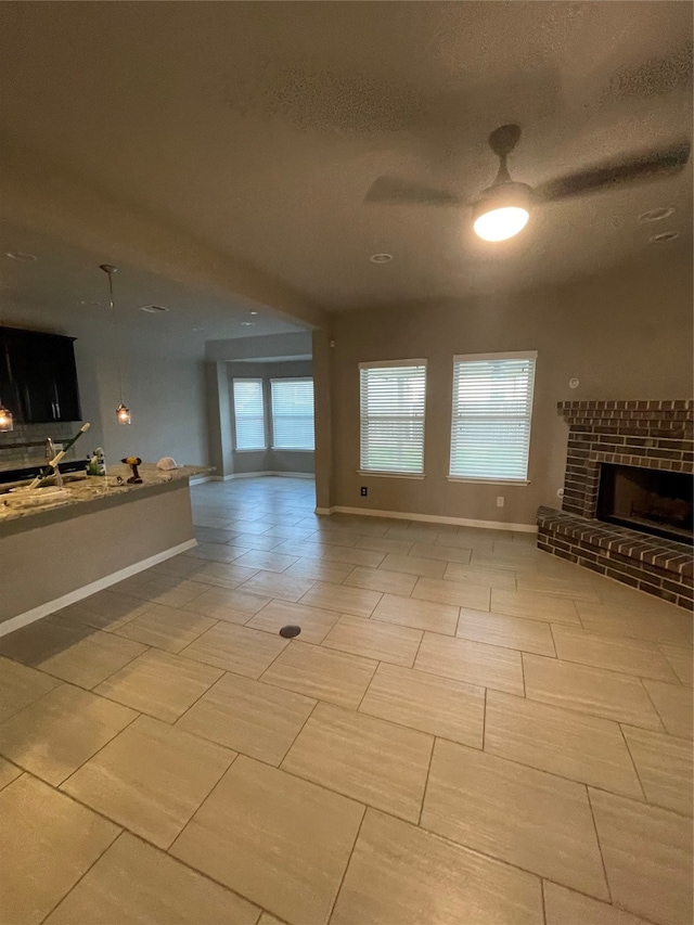 unfurnished living room featuring a healthy amount of sunlight, a brick fireplace, and light tile floors