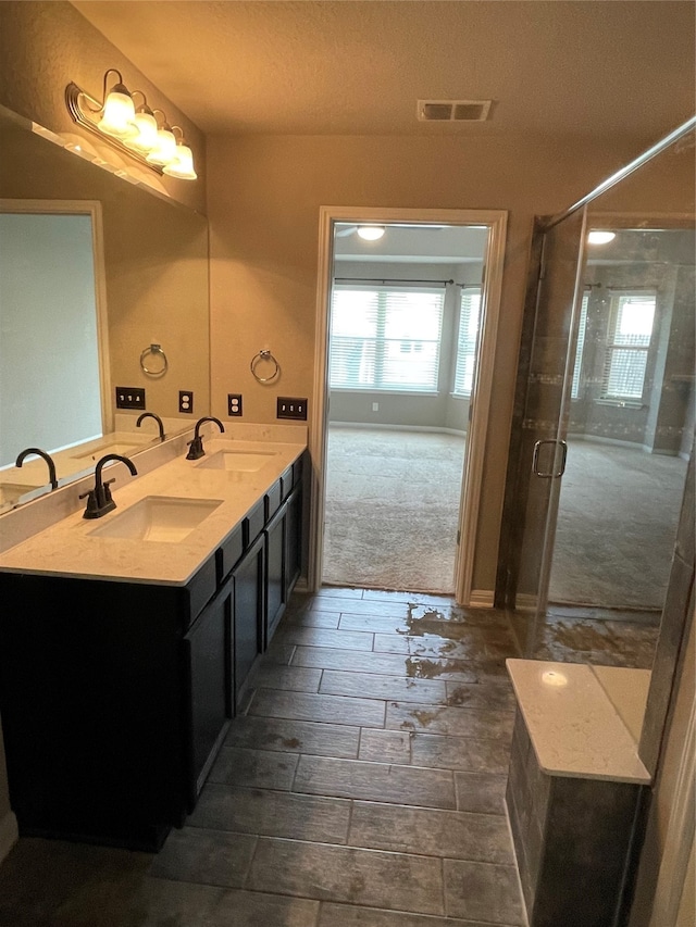 bathroom with oversized vanity, an enclosed shower, and double sink